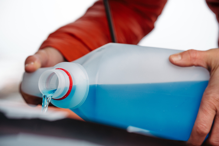 man pouring anti-freeze into a boat motor
